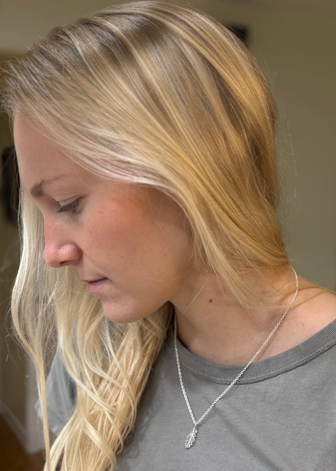 Woman with blonde hair wearing a herkimer diamond necklace, looking downwards.