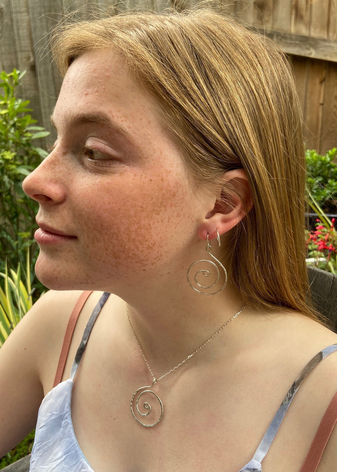 Woman wearing spiral earrings and a necklace outdoors