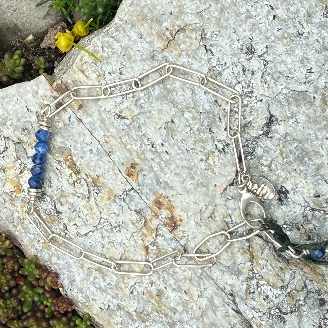 Silver bracelet with blue beads on a rocky surface